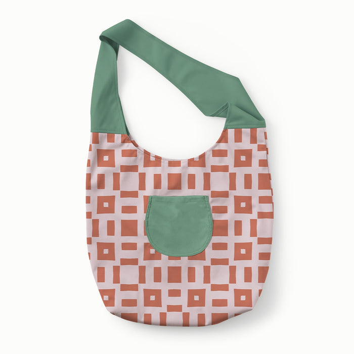 Front view of Esembly Carryall Bag in Theory colorway with a reddish brown square and line geometric pattern on a light purple background body and a green strap and pocket
