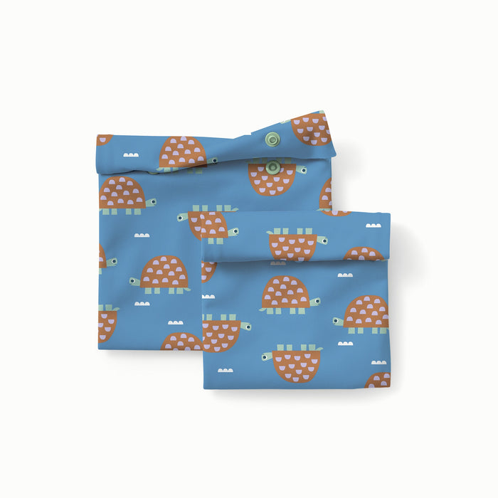 Two blue reusable storage bags with turtle pattern on a white background