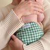 Person holding a baby wearing a green gingham cloth diaper.
