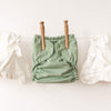 Green baby diaper with wooden buttons on a white background