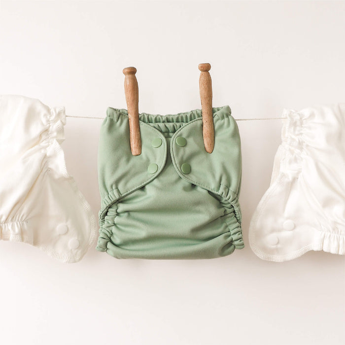 Green baby diaper with wooden buttons on a white background