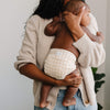 Mom holding a baby wearing a cloth diaper in Windowpane — a cream colored background with a caramel colored grid pattern