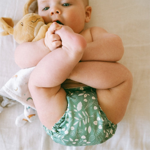 baby trying to nibble on their feet wearing an Botany (green background with white leaves) Outer