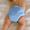 Baby laying on a bed on their stomach wearing an Esembly Outer in Cornflower (a soft mid-tone blue)